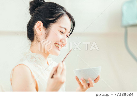 白米を食べる女性 77389634