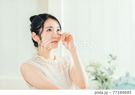 目をおさえる女性 77389685