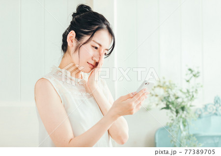 スマホを見て悩む女性(困る) スマホを見て悩む女性(困る) 77389705