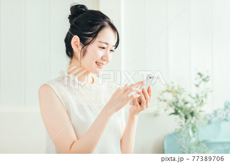 スマホを見る女性（笑顔） 77389706