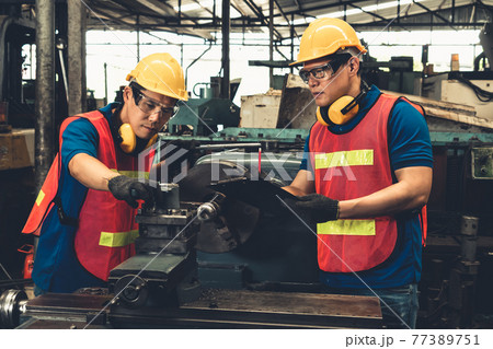 Group of skillful factory workers using machine equipment in workshop 77389751