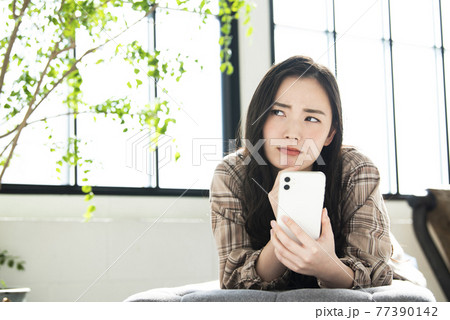 スマホで検索する若い女性　悩む 77390142