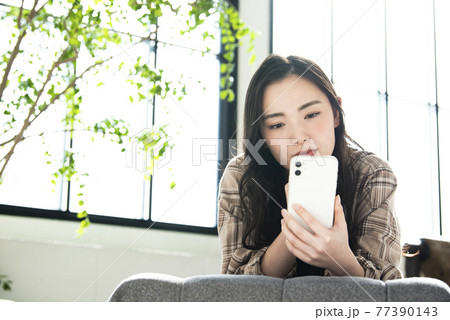 スマホで検索する若い女性　悩む 77390143