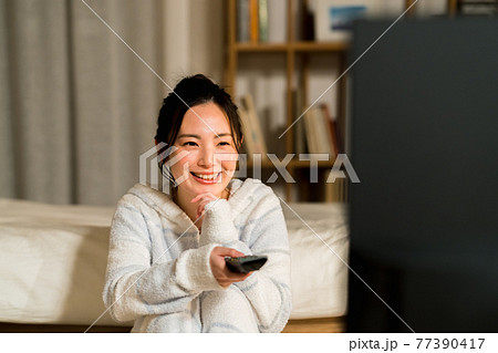 リビングでテレビを見る若い女性 リビングでテレビを見る若い女性 77390417