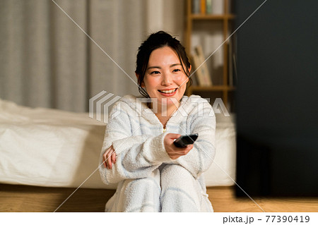 リビングでテレビを見る若い女性 リビングでテレビを見る若い女性 77390419