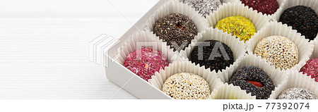 Box of vegan sweets energy balls on white wooden table. Box of vegan sweets energy balls on white wooden table. 77392074