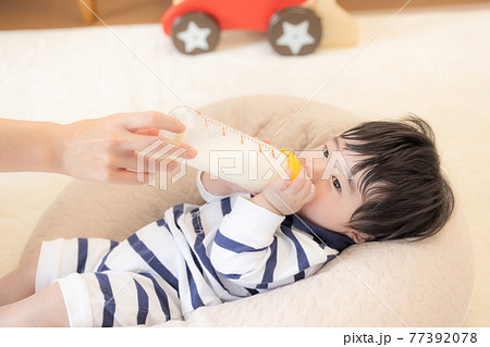 寝ころんでミルクを飲む赤ちゃん 77392078