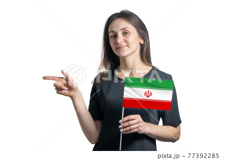 Happy young white woman holding flag Iran and points to the left isolated on a white background Happy young white woman holding flag Iran and points to the left isolated on a white background 77392285
