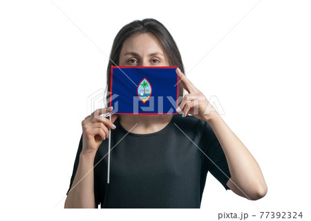 Happy young white woman holding flag Guam flag and covers her face with it isolated on a white background Happy young white woman holding flag Guam flag and covers her face with it isolated on a white background 77392324