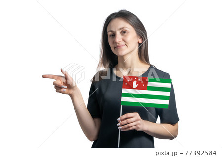 Happy young white woman holding flag Abkhazia and points to the left isolated on a white background Happy young white woman holding flag Abkhazia and points to the left isolated on a white background 77392584