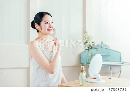 美顔ローラーを使う女性（笑顔） 77393781