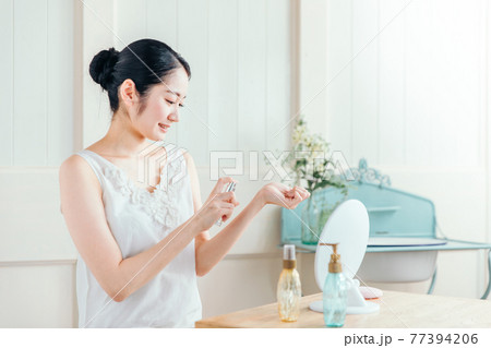 香水・虫除けをつける女性 77394206