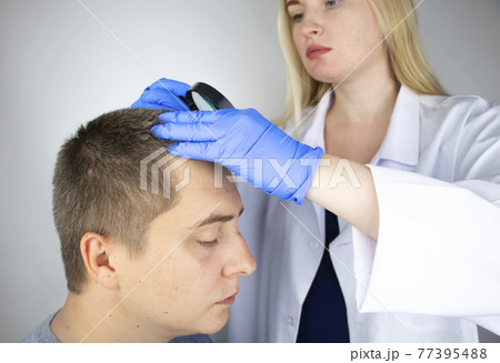 A trichologist examines the hair of a man who begins alopecia. Consultation with a dermatologist. Hair loss, alopecia, pruritus, burning head or seborrhea 77395488