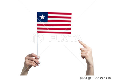 A beautiful female hand holds a Liberia flag to which she shows the finger of her other hand, isolated on white background A beautiful female hand holds a Liberia flag to which she shows the finger of her other hand, isolated on white background 77397340