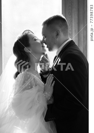 silhouettes of the bride and groom in sunlight through the glass in the door. silhouettes of the bride and groom in sunlight through the glass in the door. 77398783
