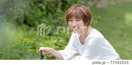 庭で植物の手入れをする若い女性　ガーデニング　バナーサイズ 77402033
