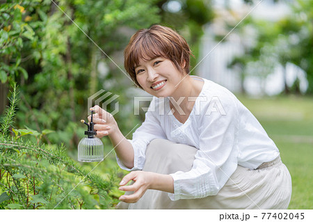 庭で植物の手入れをする若い女性　ガーデニング 77402045