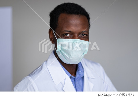 Young black man wearing a white coat and face mask Young black man wearing a white coat and face mask 77402475