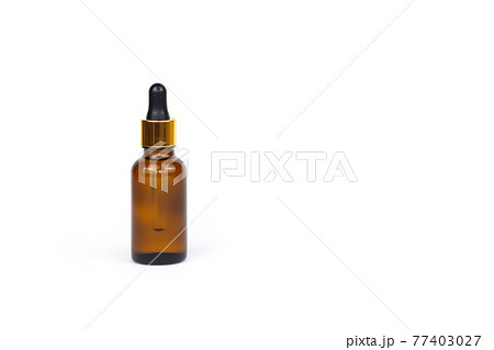 Dropping essential oil into glass bottle, bottle of hyaluronic acid with pipette isolated on white background with copy space. Serum for facial skin. Herbal mineral cosmetic. Brown package cosmetology 77403027