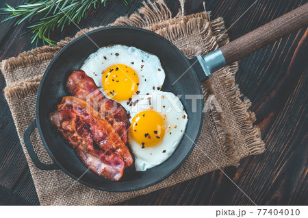 Fried eggs with bacon rashers 77404010