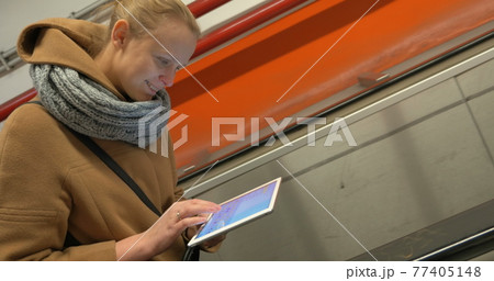 Woman on escalator using tablet computer Woman on escalator using tablet computer 77405148