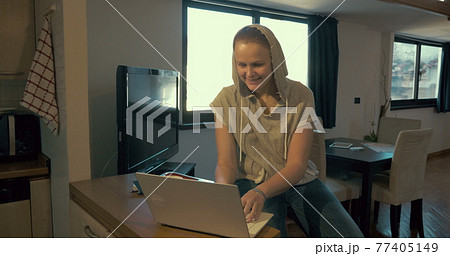 Woman at home chatting on laptop and drinking tea Woman at home chatting on laptop and drinking tea 77405149