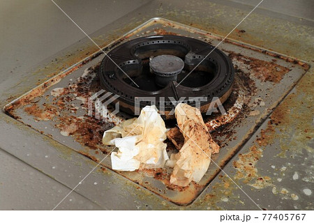 Dirty modern gas stove with cooking oil stains and burned food remnants on surface  77405767