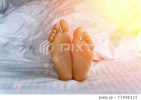 Morning and waking up. Feet under the covers in bed in the morning. Women's feet under the covers in a white bed. Relax, sleep, rest concept. Morning and waking up. Feet under the covers in bed in the morning. Women's feet under the covers in a white bed. Relax, sleep, rest concept. 77406515