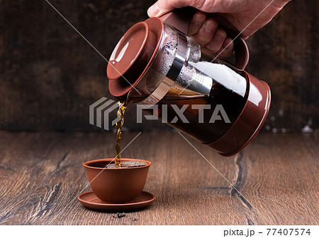Pouring freshly brewed tea into a clay cup. Brewing tea. 77407574