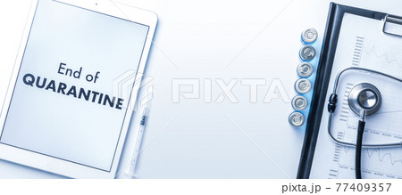Quarantine is over. Syringe with needle, hospital healthcare charts, doctor stethoscope and white tablet with text on screen for medical equipment background. End of quarantine concept. 77409357
