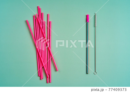 The modern trend towards caring for the environment. A pack of pink plastic beverage straws versus one reusable beverage straw with cleaning brushes 77409373