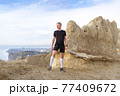 Man standing on mountains, looking on horizon 77409672