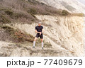 Runner standing on mountain, looking on watch 77409679