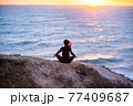 Woman meditating and doing youga at sunset 77409687
