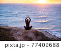 Woman meditating in lotus pose at sunset 77409688