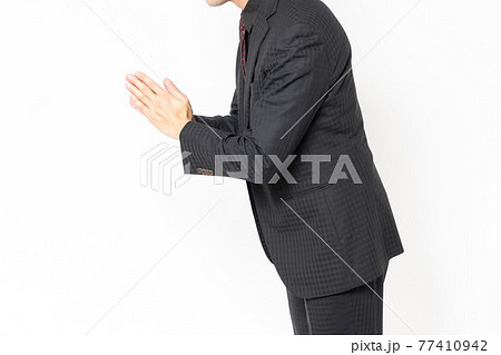 白背景の前に立って、謝罪する男性ビジネスマン 白背景の前に立って、謝罪する男性ビジネスマン 77410942