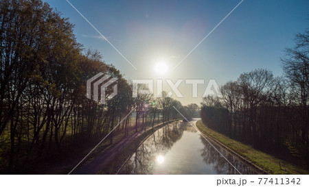 Aerial view of an Idillic river stream canal with grass banks and wild flowers and trees in a scenic Aerial view of an Idillic river stream canal with grass banks and wild flowers and trees in a scenic 77411342