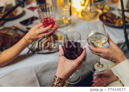Clinking glasses with alcohol and toasting, party. 77414077