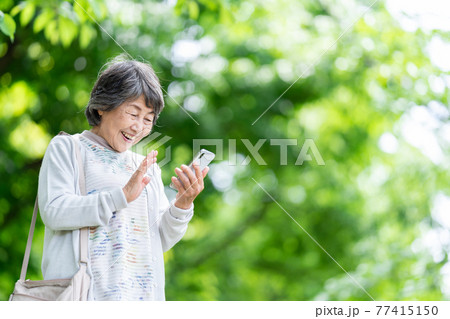 スマホを操作するシニア女性 屋外でスマホを触るお婆さん スマホを操作するシニア女性 屋外でスマホを触るお婆さん 77415150