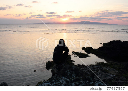 石垣島の海岸に沈む真っ赤な夕日と静かな海 77417597