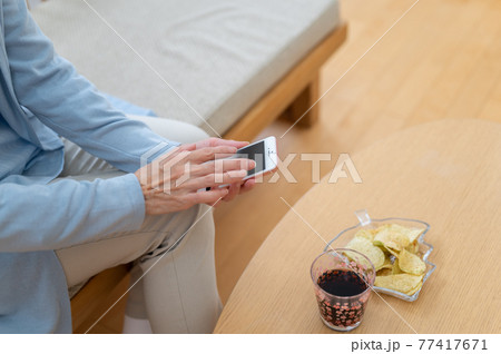 自粛生活中お家でスマホを使うシニア女性 77417671