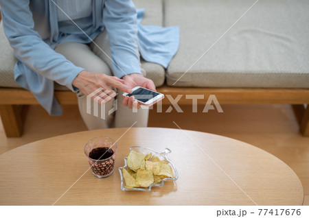 自粛生活中お家でスマホを使うシニア女性 自粛生活中お家でスマホを使うシニア女性 77417676
