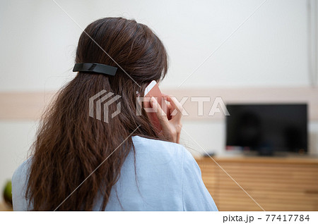 自粛生活中スマホで電話してるミドル女性後ろ姿の写真素材