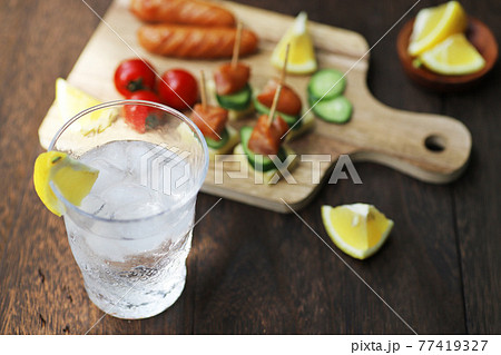 グラスに注がれた冷たいハイボールとおつまみ グラスに注がれた冷たいハイボールとおつまみ 77419327