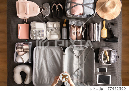 Top view woman hands getting ready to travel vacation packing suitcase use konmari method Top view woman hands getting ready to travel vacation packing suitcase use konmari method 77422590