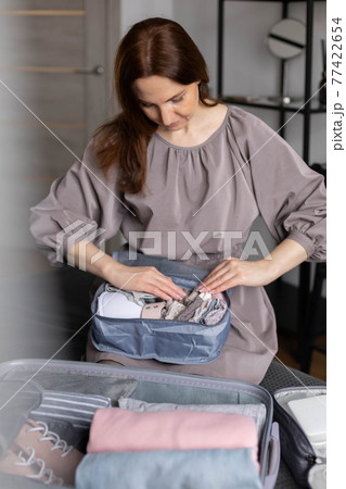 Unidentified woman puts lingerie in trip storage container use konmari method packing suitcase 77422654