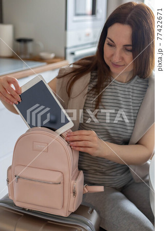 Female hands putting tablet pc into comfortable bag storage get ready to business trip or vacation 77422671