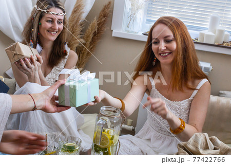 Happy woman celebrating birthday in hippie bohemian style table serving of food gifts from friends 77422766