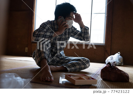 電話する具合が悪い若者 77423122