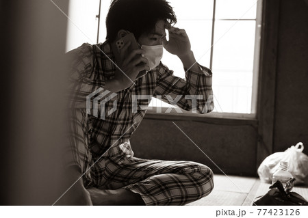 電話する具合が悪い若者 77423126
